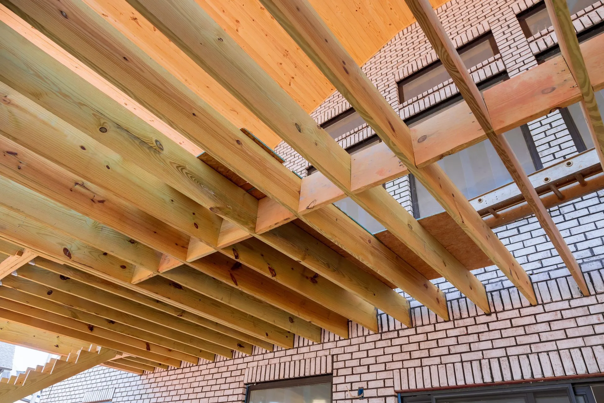 Wooden ceiling beams under construction above a brick wall and window openings.
