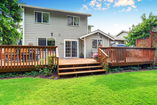 Backyard deck with wooden railings and steps leading to a gray two-story house