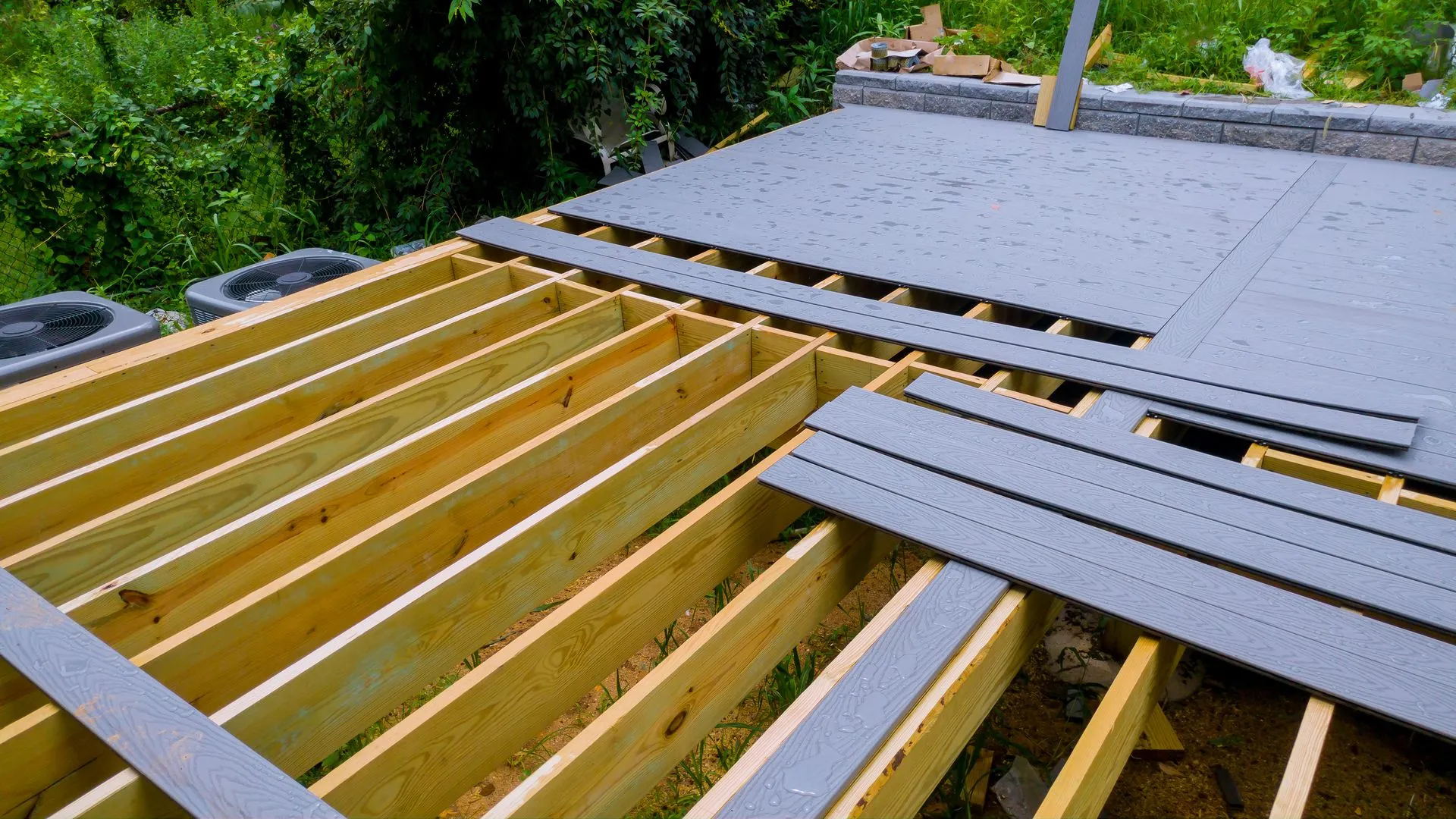 Roof under construction with wooden joists and gray boards laid over part of the frame